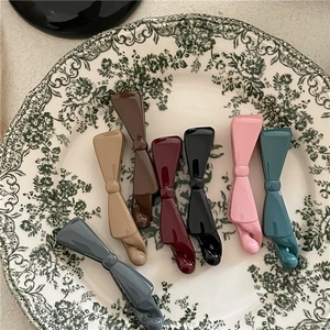 Close-up of assorted Morandi colored plastic bow banana clips on a vintage floral plate