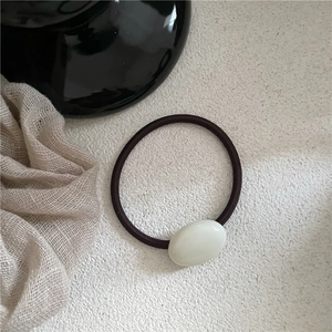 Detail of cream oval stone bead on high-elasticity brown hair tie with soft aesthetic