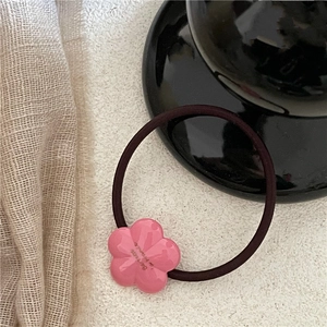 Detailed close-up of pink flower resin charm with gold lettering on elastic hair tie