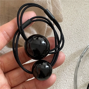 Close-up of black beaded double-strand elastic hair tie held in hand with soft lighting