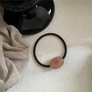Pink oval resin bead on high elastic dark brown hair tie set against white texture