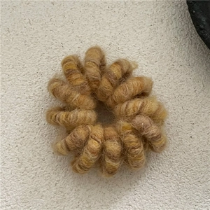Gros plan sur un élastique à cheveux spirale marron enveloppé de laine douce et pelucheuse