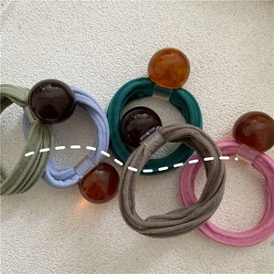 Detail of five-piece cream elastic hair ties with amber resin beads and knitted texture
