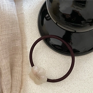 Detailed macro view of the cream-colored flower charm on a high-elastic brown hair tie