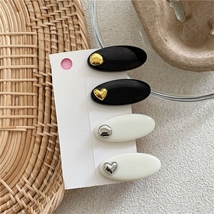Détail des motifs cœur et points sur les pinces à cheveux ovales noires et blanches