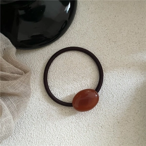 Macro shot of an elegant amber resin oval bead on a high-elastic brown hair tie