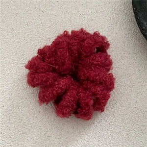 Détail de l'élastique à cheveux en laine spirale rouge foncé avec texture douce d'hiver