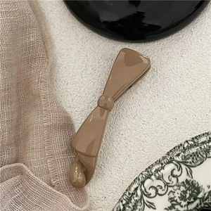 Detailed view of glossy brown plastic bow banana hair clip on vintage ceramic plate
