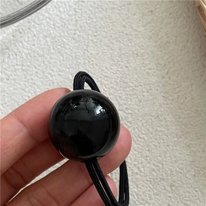 Detail view of a large glossy black bead on double-strand high elastic hair tie band