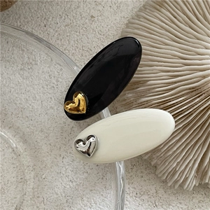 Détail de barrettes ovales élégantes avec clous en cœur en finitions noir et crème résine