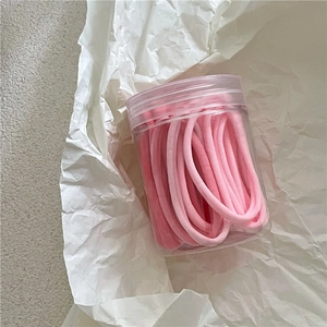 Détail d'élastiques à cheveux dégradés roses rangés dans un pot en plastique transparent