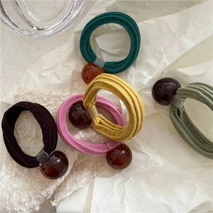 Detailed close-up of colorful elastic hair ties with smooth amber resin beads on lace