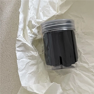 Gros plan d'élastiques noirs pour cheveux dans un contenant de rangement cylindrique
