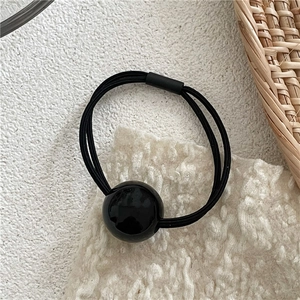 Detailed view of black multi-strand elastic hair tie with a large polished bead detail