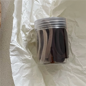 Gros plan d'élastiques à cheveux crème assortis dans un pot de rangement transparent
