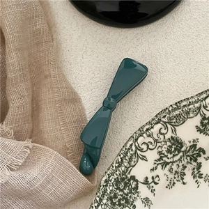 Detail of dark green glossy plastic bow banana clip on decorative ceramic plate