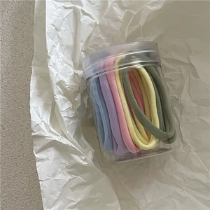 Gros plan d'élastiques à cheveux pastel assortis dans un pot de rangement transparent