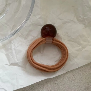 Detailed close-up of brown elastic hair tie with a translucent amber-like resin bead