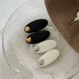 Détail de barrettes ovales noires et blanches avec décorations de cœurs dorés et argentés