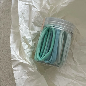 Détail des chouchous en tissu éponge bleu et menthe dans un pot de rangement clair