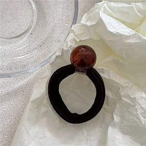 Close-up of thick black elastic hair tie with amber textured resin bead detail