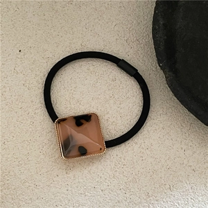 Detail of black elastic hair tie with square tortoiseshell resin and golden bead trim
