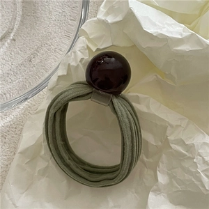 Detailed close-up of olive green elastic hair tie with a dark cherry red polished bead