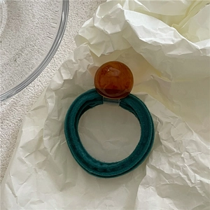 Macro shot of dark green velvet hair tie with an amber marble resin bead ornament