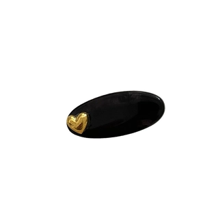 Barrette à cheveux ovale noire élégante ornée d'un cœur doré sur fond blanc pur