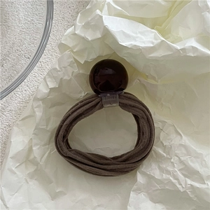 Close-up of a dark coffee elastic hair tie with a large polished geometric round bead