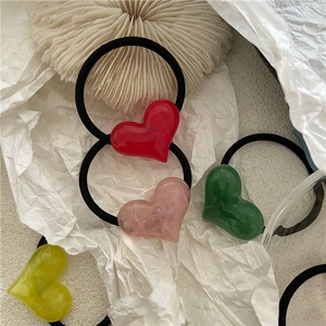 Detail shot of colorful resin heart charms on elastic black hair ties for women