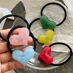 Detail of colorful marble-textured acrylic heart hair ties on black elastic bands