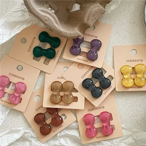 Close-up of colorful resin bow hair clips set on paper card in natural earthy tones