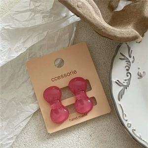 Detail of pink resin bow earrings on a handmade display card with a soft jelly texture