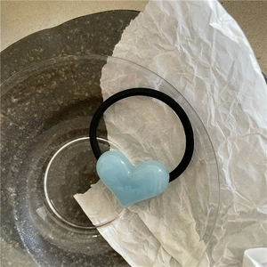 Detailed shot of a light blue resin heart charm on a black high-elastic hair tie