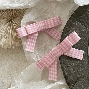 Pink plaid bow hair clips in preppy style with soft fabric streamers on stone tray