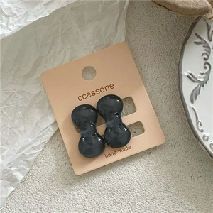 Detail view of dark grey plastic bow hair clips on pink card packaging display