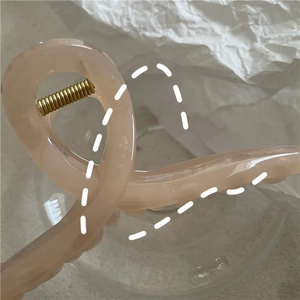 Detail of pink resin hair claw clip showing translucent texture and gold metal spring