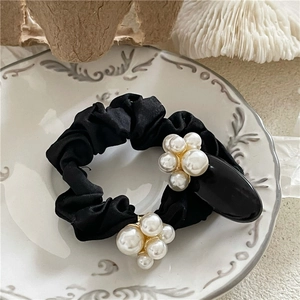 Elegant black satin scrunchie with white pearls in a decorative vintage ceramic dish