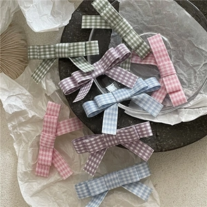 Close-up detail of checkered fabric bow hair clips in pastel pink and blue tones