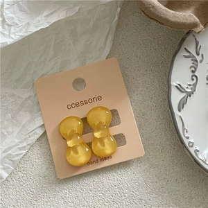 Detail view of amber resin bow earrings displayed on a premium retail card