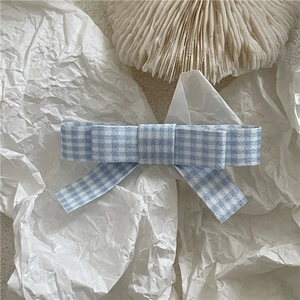 Detail of blue and white checkered fabric bow hair clip with a vintage preppy style