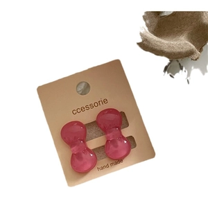 Pair of cute pink translucent plastic bow hair clips on a cream display card for girls