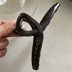 Detail of a large coffee tortoise shell hair claw clip with cross-twist design