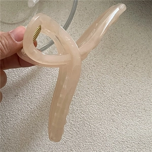Detailed close-up of jelly texture flesh pink hair claw clip with golden metal spring