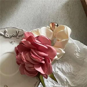Λεπτομέρεια από ροζ λουλούδι scrunchie με σατέν πέταλα και χρυσό μενταγιόν