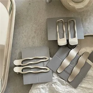 Détail de barrettes à cheveux en métal argenté mat ondulées et géométriques sur carte