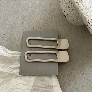 Détail de barrettes à cheveux évidées dorées mates aux bords ondulés en métal