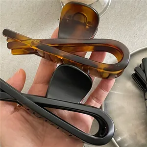 Détail de pinces à cheveux en résine ambrée et noir mat avec un design torsadé