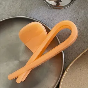 Gros plan de pinces à cheveux géométriques minimalistes en fini pêche et beige mat